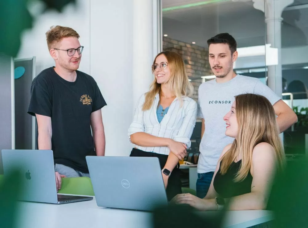 Ihre Agentur für Online-Marketing-Konzeption Vier Kolleginnen und Kollegen besprechen eine Online-Marketing-Konzeption an Laptops in einem modernen Büro