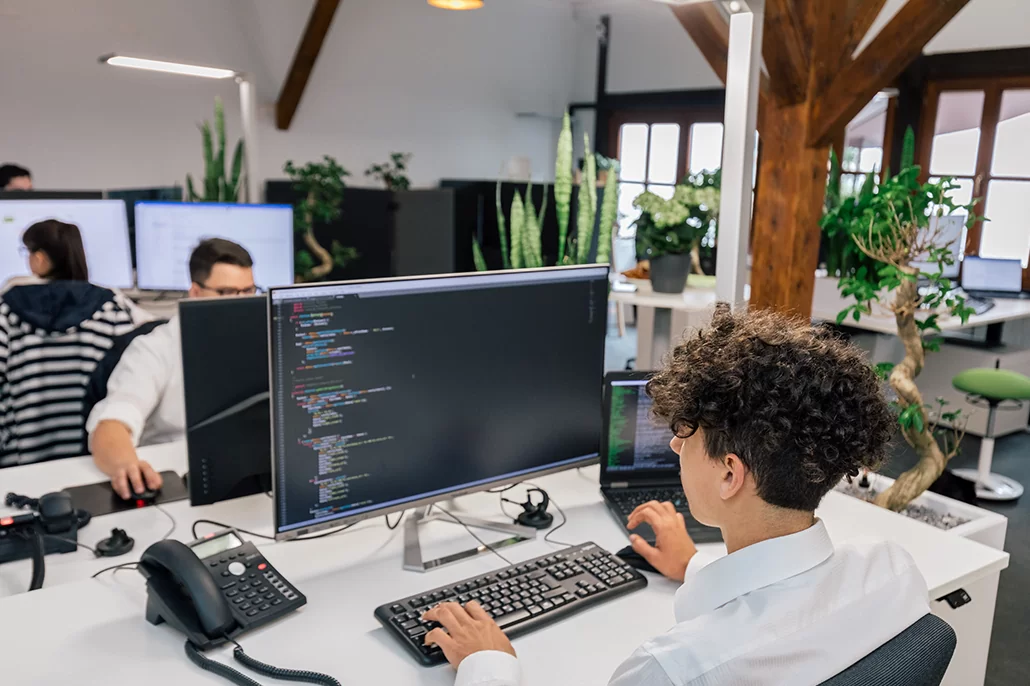 Arbeitsplatz Mitarbeiter sitzt am Computer und bearbeitet Quellcode