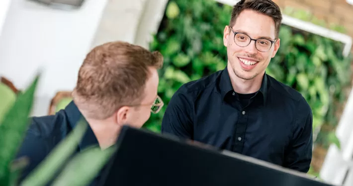 Zwei Online-Marketing-Profis besprechen sich vor einem Computer