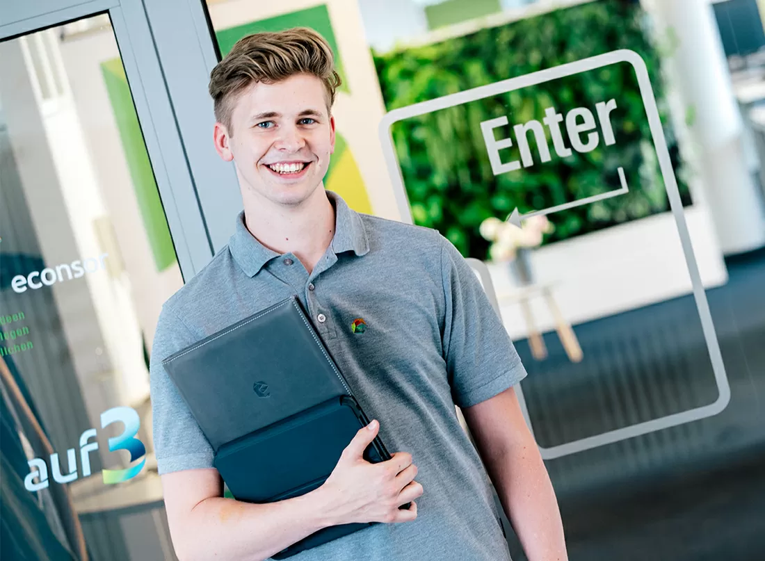 Mitarbeiter steht mit einem Ordner vor dem Besprechungsraum