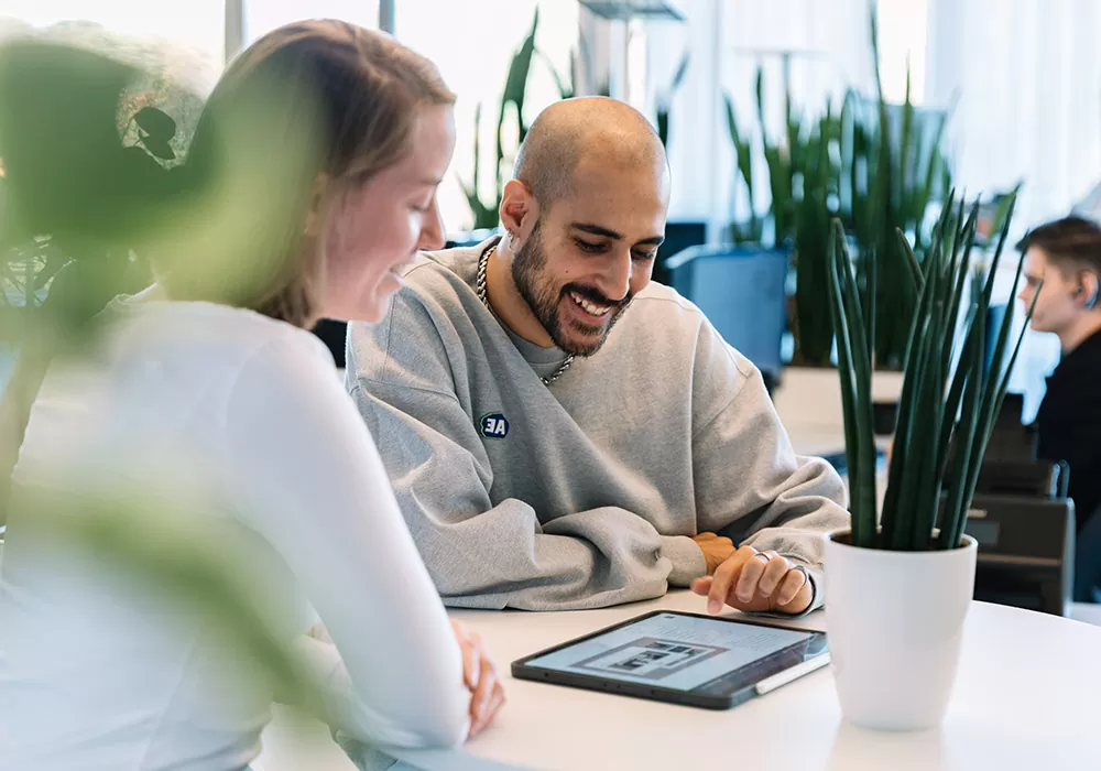 SEO-Agentur in Mannheim Zwei Personen sitzen an einem Tisch und schauen auf ein Tablet.
