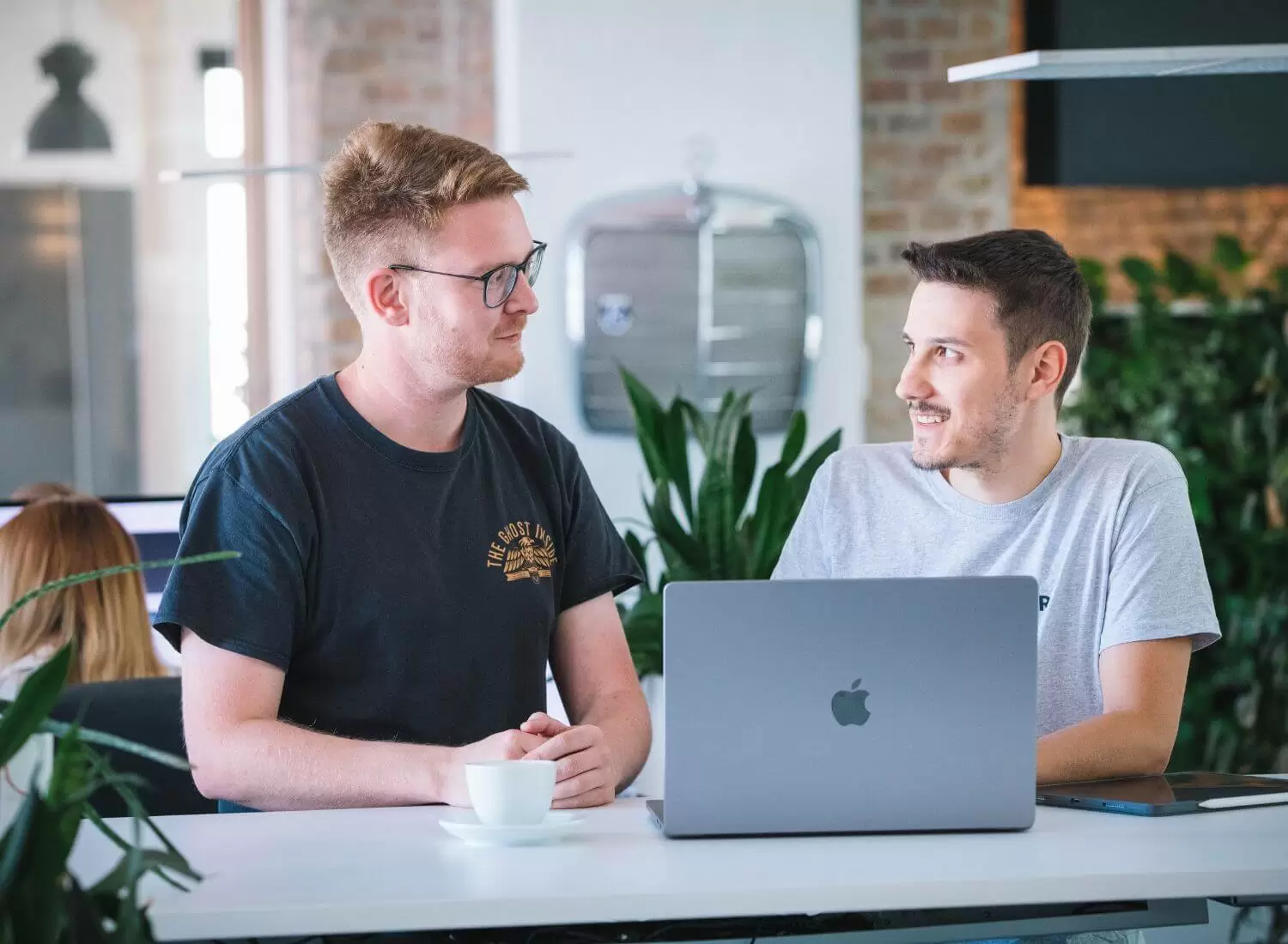 WordPress-Spezialisten in Mannheim Zwei junge Männer vor einem Laptop an einem Hochtisch in einem modernen Büro.