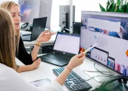 Zwei Mitarbeiter betrachten ein Webdesign auf einem Rechner