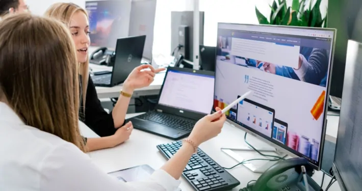 Zwei Mitarbeiter betrachten ein Webdesign auf einem Rechner