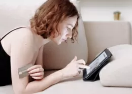 Frau auf Sofa kauft in einem Onlineshop ein.